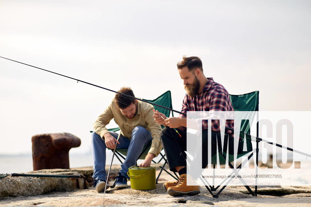 Freunde anpassung angelruten mit köder auf pier freizeit und menschen konzept - freunde oder fischer anpassung angelruten mit köder auf pier (License=RF) ,model released, Symbolfoto