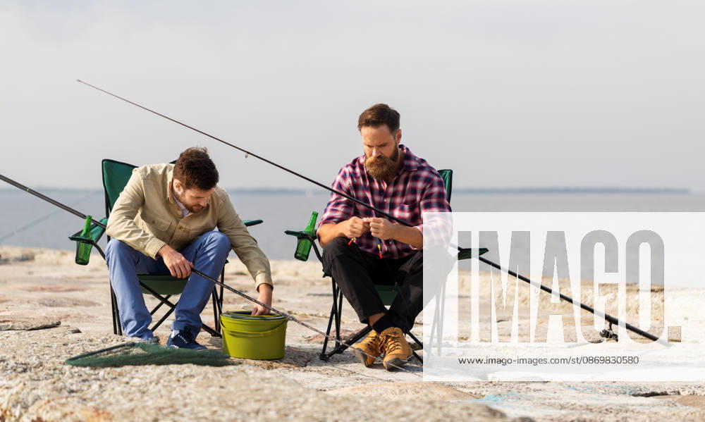 Freunde anpassung angelruten mit köder auf pier freizeit und menschen konzept - freunde oder fischer anpassung angelruten mit köder auf pier (License=RF) ,model released, Symbolfoto
