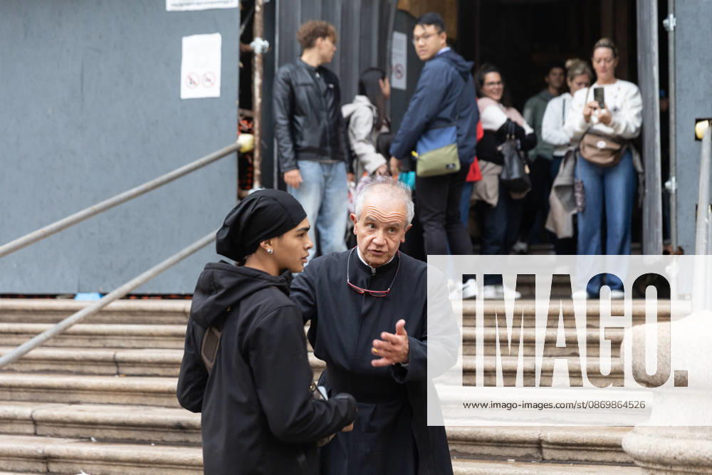IPA89867620 - Milan, October 18, 2026: More Clashes and Looting in Downtown Milan the Day After the Protest; pictured: a priest closes the church to protesters seeking shelter