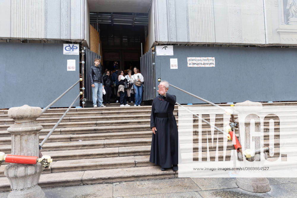 IPA89867625 - Milan, October 18, 2026: More Clashes and Looting in Downtown Milan the Day After the Protest; pictured: a priest closes the church to protesters seeking shelter