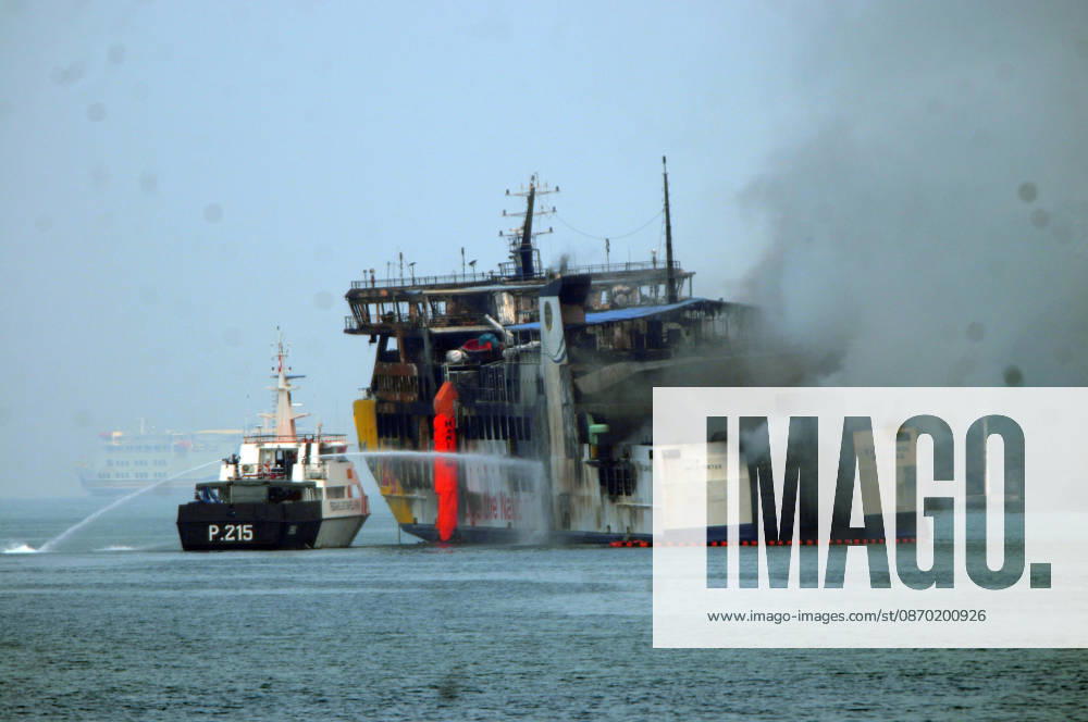 Efforts are underway to extinguish a fire that broke out on a passenger ferry in Indonesia s Cilegon PELABUHAN MERAK, CILEGON, INDONESIA - OCTOBER 21: Fireboats take turns spraying water onto the passenger ferry KMP Batumandi to cool down the vessel after it caught fire while preparing to dock off Merak Port in Cilegon, Banten, Indonesia on Wednesday, October 21, 2026. The vessel caught fire on Tuesday, October 20, and rescue operations remain underway as the ship continues to emit smoke. Water is continuously sprayed to cool the vehicle deck containing numerous cars, motorcycles, buses, and trucks, while authorities confirm no fatalities have been reported. Dasril Roszandi Anadolu Pelabuhan Merak Indonesia. Editorial use only. Please get