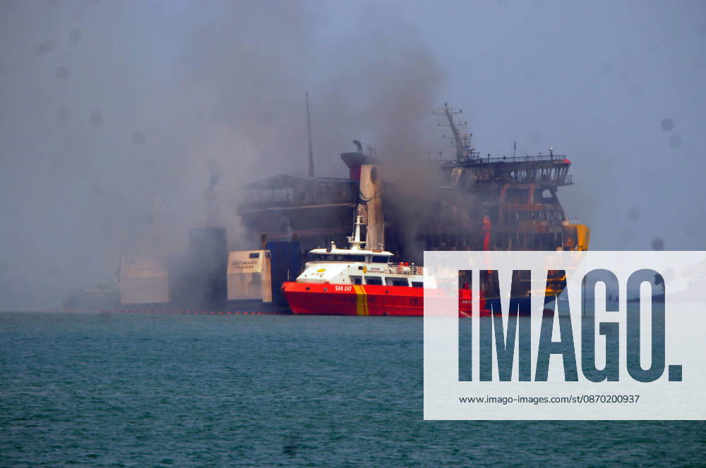 Efforts are underway to extinguish a fire that broke out on a passenger ferry in Indonesia s Cilegon PELABUHAN MERAK, CILEGON, INDONESIA - OCTOBER 21: Fireboats take turns spraying water onto the passenger ferry KMP Batumandi to cool down the vessel after it caught fire while preparing to dock off Merak Port in Cilegon, Banten, Indonesia on Wednesday, October 21, 2026. The vessel caught fire on Tuesday, October 20, and rescue operations remain underway as the ship continues to emit smoke. Water is continuously sprayed to cool the vehicle deck containing numerous cars, motorcycles, buses, and trucks, while authorities confirm no fatalities have been reported. Dasril Roszandi Anadolu Pelabuhan Merak Indonesia. Editorial use only. Please get