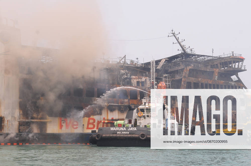 Efforts are underway to extinguish a fire that broke out on a passenger ferry in Indonesia s Cilegon PELABUHAN MERAK, CILEGON, INDONESIA - OCTOBER 21: Fireboats take turns spraying water onto the passenger ferry KMP Batumandi to cool down the vessel after it caught fire while preparing to dock off Merak Port in Cilegon, Banten, Indonesia on Wednesday, October 21, 2026. The vessel caught fire on Tuesday, October 20, and rescue operations remain underway as the ship continues to emit smoke. Water is continuously sprayed to cool the vehicle deck containing numerous cars, motorcycles, buses, and trucks, while authorities confirm no fatalities have been reported. Dasril Roszandi Anadolu Pelabuhan Merak Indonesia. Editorial use only. Please get