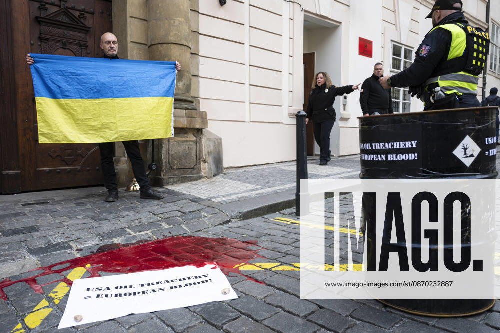 Activists from the Kaputin group poured artificial blood (an easily washable food coloring) from an oil drum during a brief visual performance in front of the U.S. Embassy in Prague on October 21, 2026. There is a poster on the ground that reads: USA OIL TREACHERY = EUROPEAN BLOOD! (CTKxPhoto MichalxKamaryt) CTKPhotoP2026102105260 CTKPhotoP2026102105260