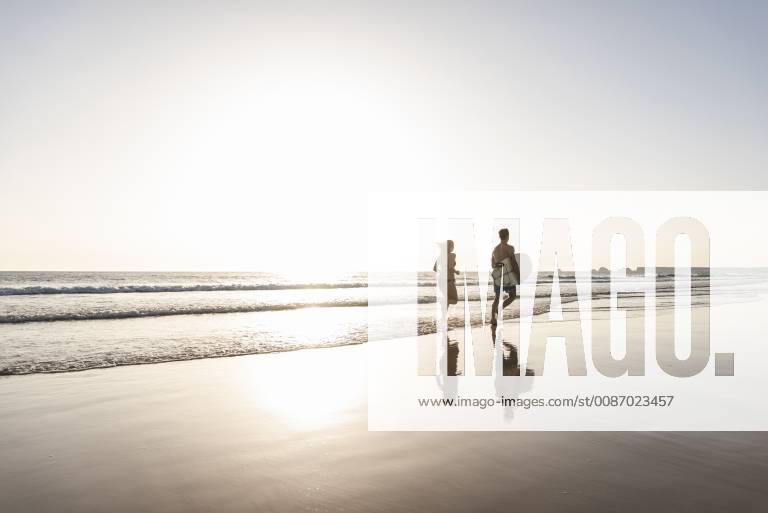 Young couple running on beach, carrying surfboard model released Symbolfoto UUF15121