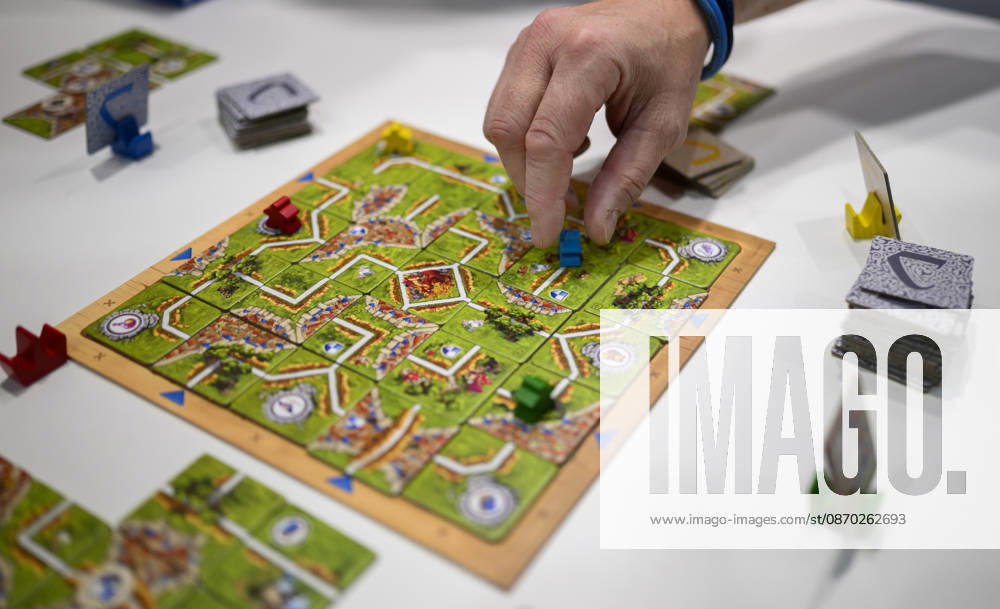 Feature, das Spiel Carcassonne Labyrinth aus der Verlagskooperation Ravensburger und Hans im Glück, eine Hand zieht einen Spielstein, Neuheitenschau, am 21.10.2026 Messe SPIEL Essen vom 22.10 - 25.10.2026 in E s s e n Deutschland. Grugahalle