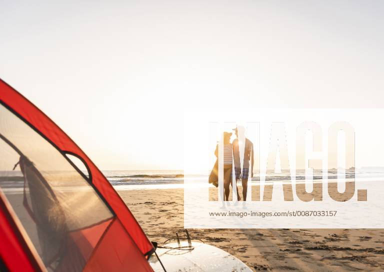 Romantic couple camping on the beach, doing a beach stroll at sunset model released Symbolfoto UUF15150
