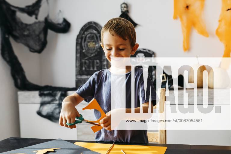 Smiling little boy cutting out for Halloween decoration at home model released Symbolfoto property released JRFF01887