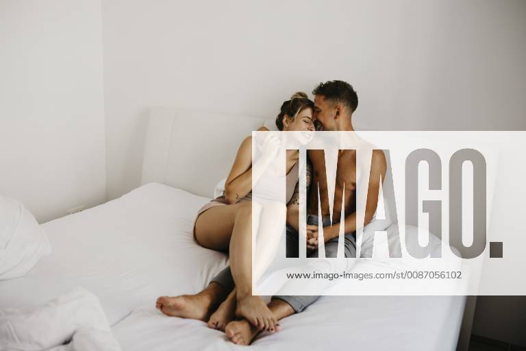 Happy young couple sitting in bed model released Symbolfoto property released LHPF00037