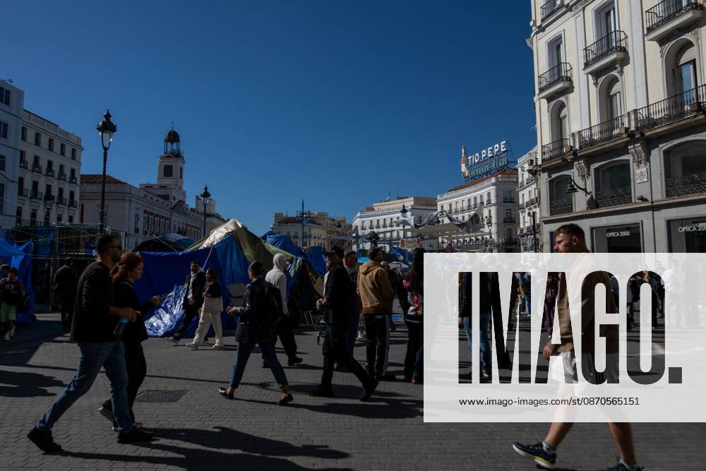 People walk in front of the tents of an encampment for decent housing, set up at Puerta del Sol..Tents remain set up by housing rights activists, who organized the occupation of the square in response to the eviction of Maricarmenâ€a woman in her eightiesâ€from her home, carried out by a real estate investment fund. Madrid Spain - ZUMAs197 20261023_aaa_s197_154