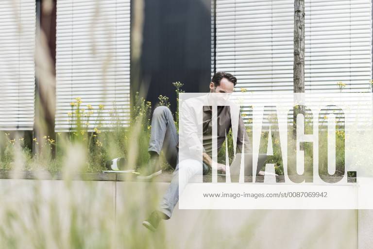 Portrait of smiling businessman working with laptop outdoors model released Symbolfoto property released UUF12113