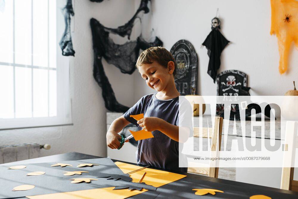 Smiling little boy cutting out for Halloween decoration at home model released Symbolfoto property released JRFF01886