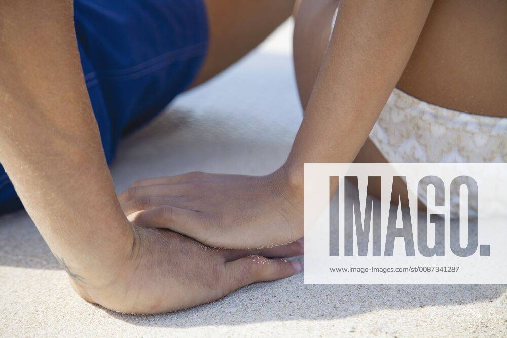 Couple holding hands at the beach, cropped