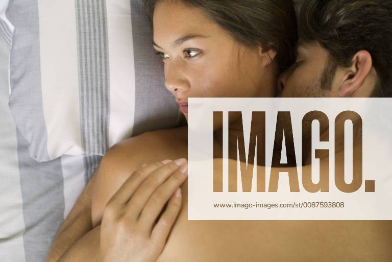 Young couple being intimate in bed, woman looking away