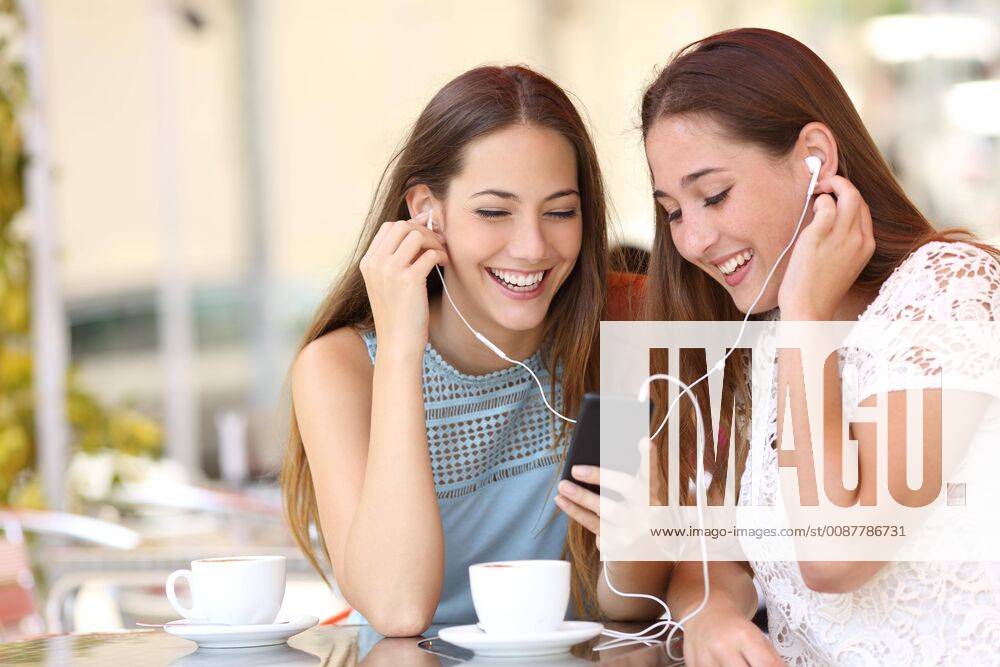 Friends sharing and listening to music with smartphone model released Symbolfoto