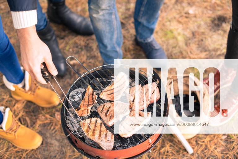 People cooking meat on charcoal grill