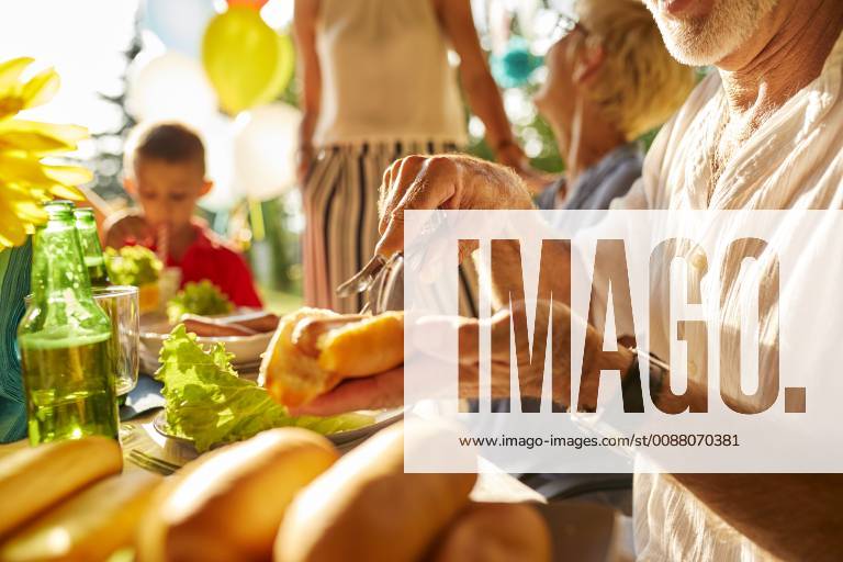 Senior man preparing a hot dog on a garden party model released Symbolfoto property released ZEDF01618