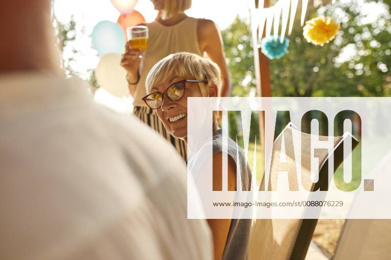 Smiling mature woman looking at husband on a garden party model released Symbolfoto property released ZEDF01624