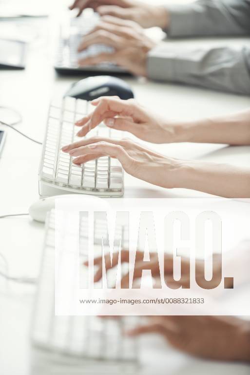 Office workers using computer keyboards, cropped
