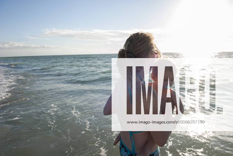 Mother wading in water with toddler boy