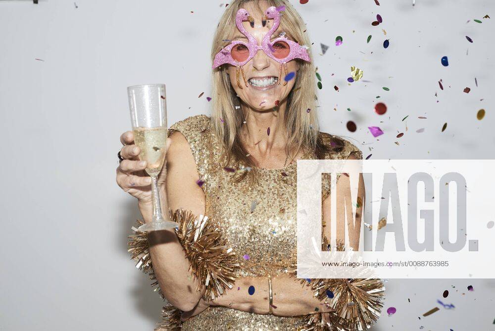 Senior woman wearing golden dress and flmingo shaped glasses, celebtraing New Year s Eve model released Symbolfoto property released IGGF00691
