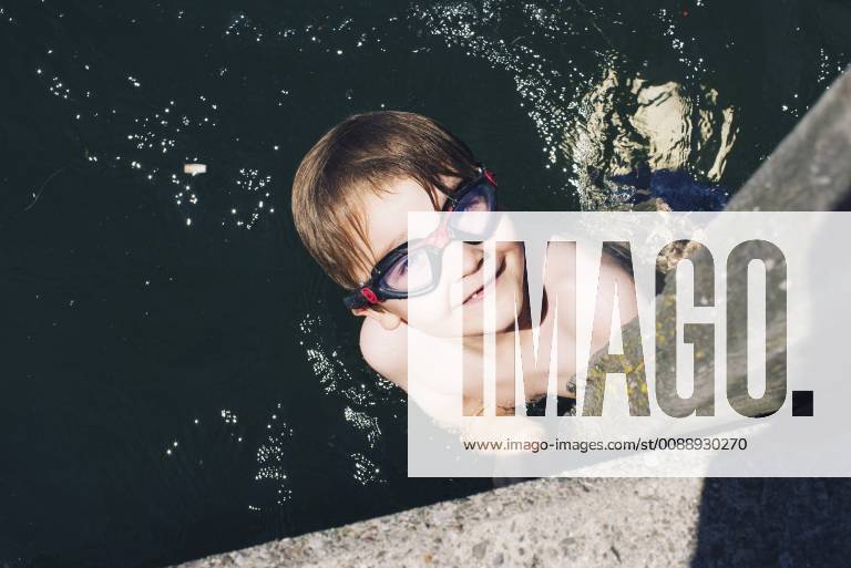 Boy with goggles swimming in water