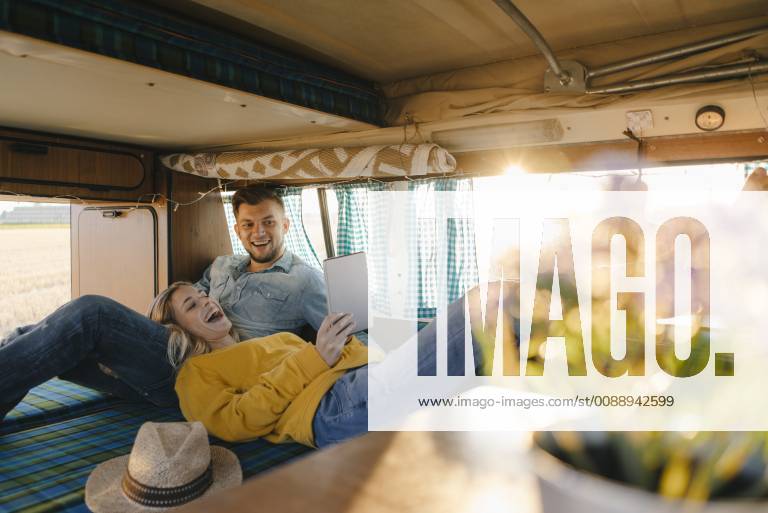 Happy young couple looking at tablet inside camper van model released Symbolfoto GUSF01409