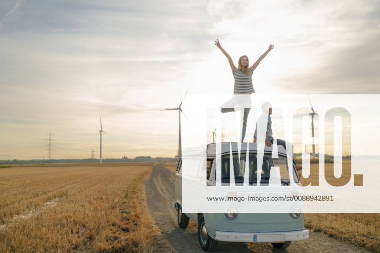 Young couple on roof of a camper van in rural landscape model released Symbolfoto GUSF01643