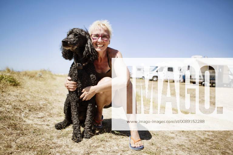 Frau umarmt ihren Hund, Königspudel, auf einem Campingplatz, Portbail, Normandie, Frankreich, Europa
