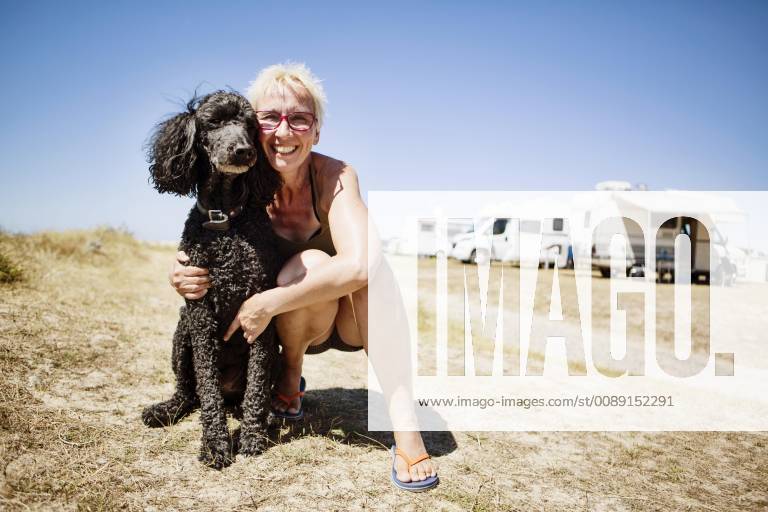 Frau umarmt ihren Hund, Königspudel, auf einem Campingplatz, Portbail, Normandie, Frankreich, Europa