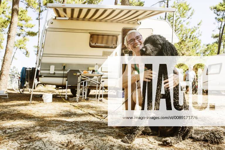 Frau hockt lachend mit ihrem Hund, Königspudel, vor Wohnmobil auf einem Campingplatz, le Gurp, Grayan-et-l Hopital, Aquitanien, Gironde, Frankreich, Europa