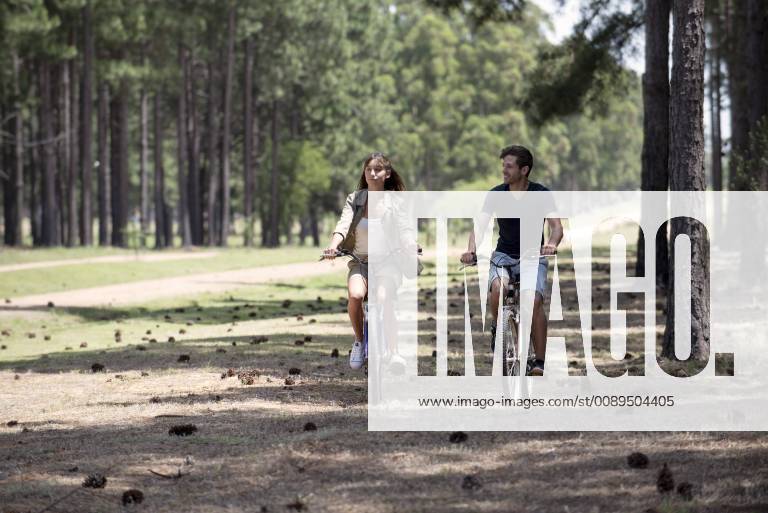 IMAGO Creative, Jahreszeit Sommer, Hitze IMAGO Creative, Sommer, Schatten-Plätze bei Hitze Young couple cycling in pine forest