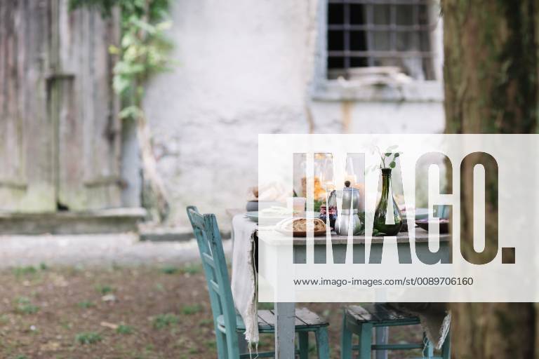 Laid garden table with candles next to a cottage ALBF00719