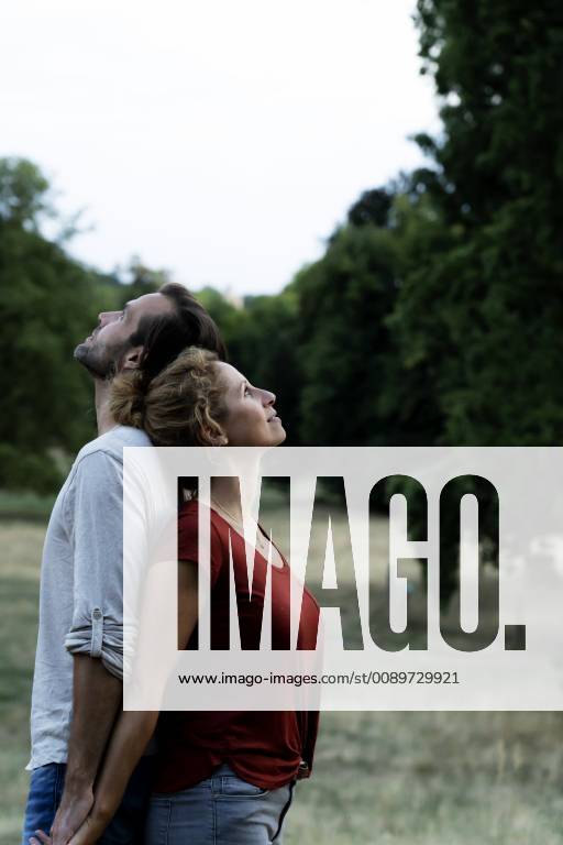 Happy couple standing in nature, back to back model released Symbolfoto HHLMF00588