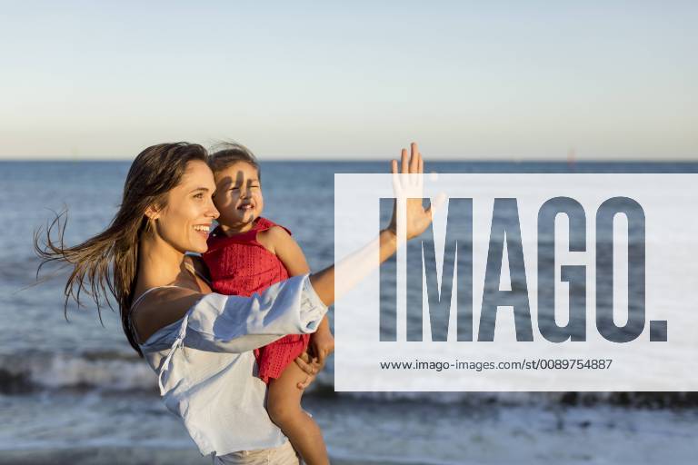 Mother and daughter standing on the beach at sunset model released Symbolfoto MAUF01929