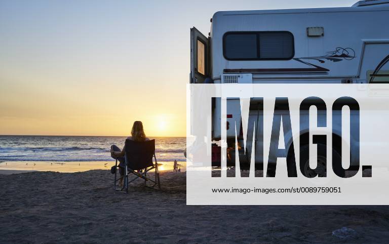 Chile, Arica, woman sitting next to camper on the beach at sunset model released Symbolfoto property released SSCF00079
