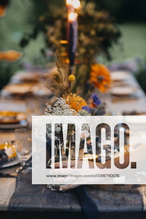 Hand placing flower vase on festive laid table with candles outdoors model released Symbolfoto ALBF00703