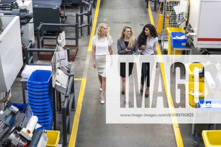 Three women with tablet walking and talking in factory shop floor model released Symbolfoto property released DIGF05291