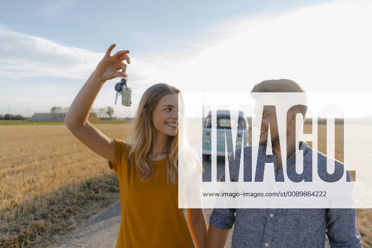 Young couple with car key on dirt track at camper van in rural landscape model released Symbolfoto GUSF01456