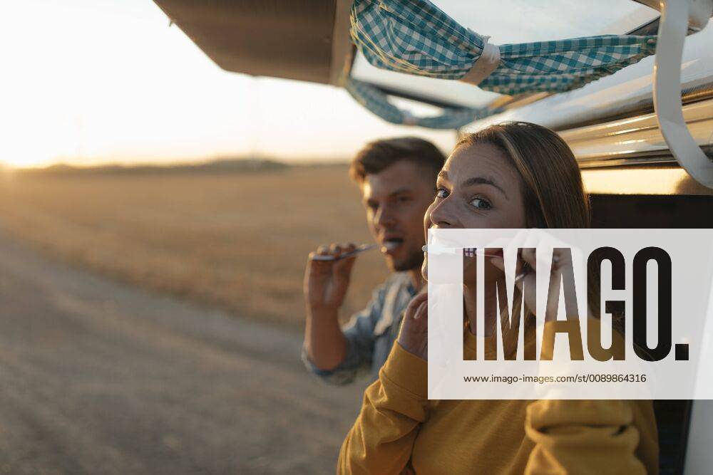 Couple brushing teeth at camper van in rural landscape at sunset model released Symbolfoto GUSF01542