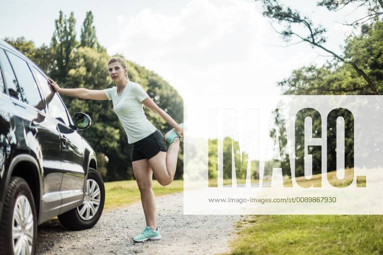 Sportive young woman stretching at a car in a park model released Symbolfoto MOEF01529