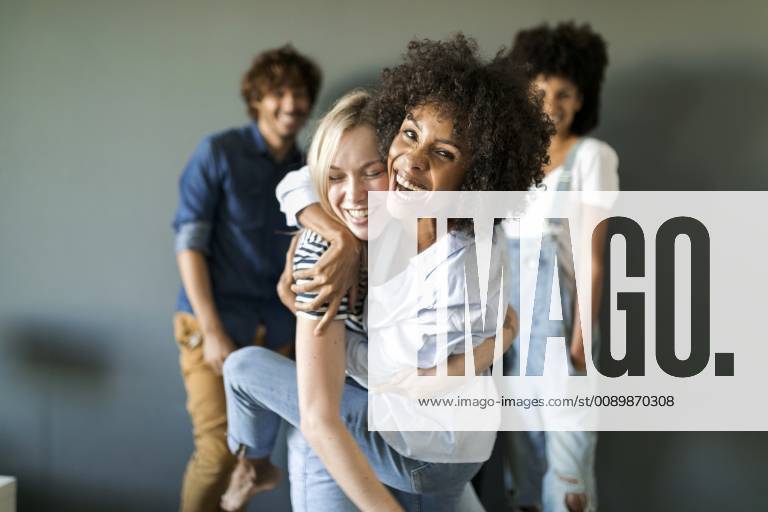 Two happy women hugging with friends in background model released Symbolfoto property released VABF01748