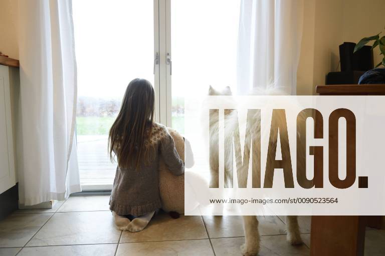 Back view of girl and her dog looking through French door model released Symbolfoto property released ECPF00282
