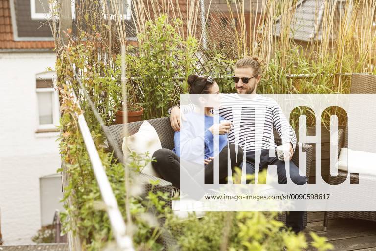 Young couple relaxing on their balcony, sitting on couch model released Symbolfoto property released PESF01157