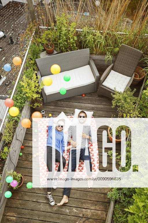 Young couple relaxing on their balcony, lying on blanket with arms around model released Symbolfoto property released PESF01170
