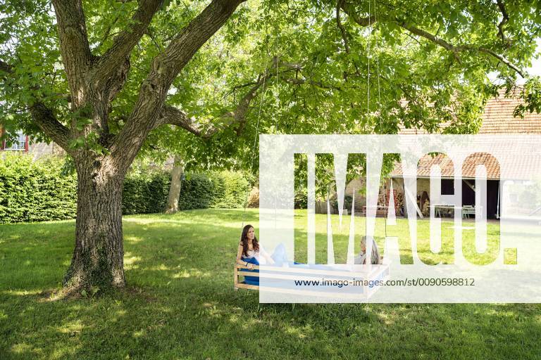 Two women relaxing on a hanging bed in garden model released Symbolfoto property released PESF01260