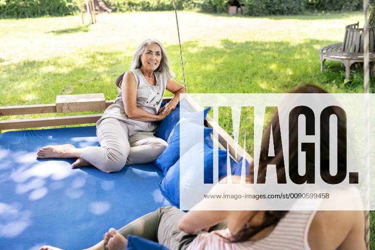 IMAGO Creative, Sommer, Schatten-Plätze bei Hitze Two women relaxing on a hanging bed in garden model released Symbolfoto property released PESF01371