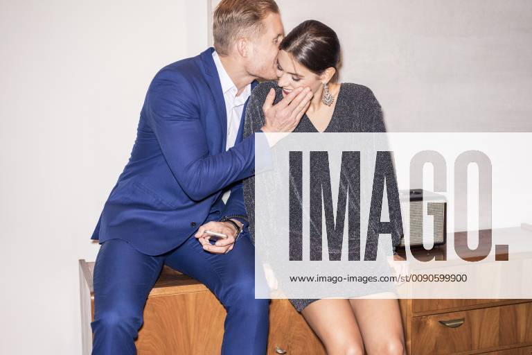 Young couple sitting on sideboard whispering model released Symbolfoto PNEF01204
