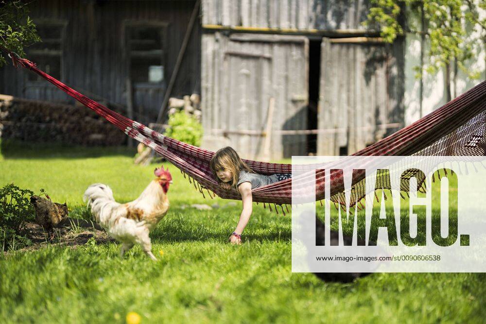 Girl relaxing in hammock in garden of a farm with chicken in foreground model released Symbolfoto property released SBOF01699