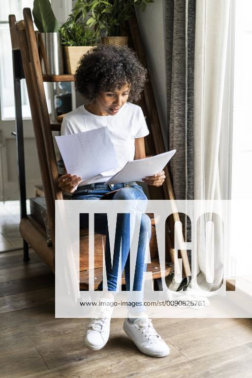 Woman sitting on steps at home looking at document model released Symbolfoto property released GIOF05667
